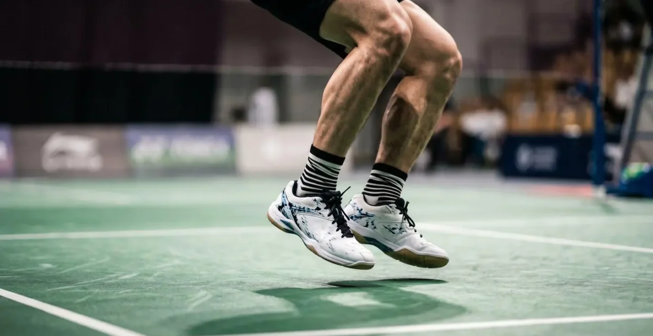 Gros plan sur les pieds et les jambes d'un joueur de badminton effectuant un split step