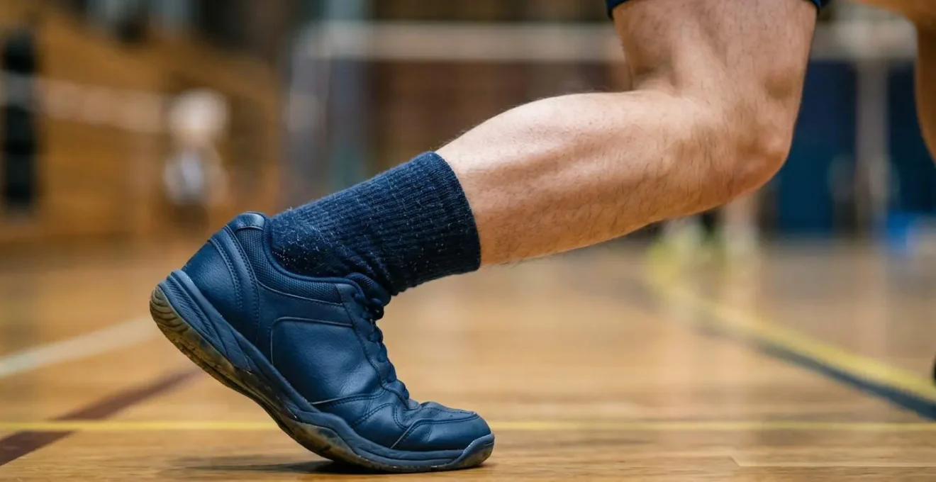 Vue rapprochée montrant l'alignement correct du genou par rapport au pied lors d'une fente au badminton