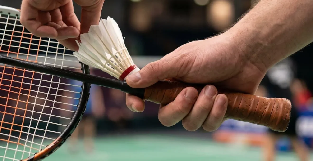 Gros plan sur la prise de raquette et le positionnement des doigts pour un service court de précision au badminton