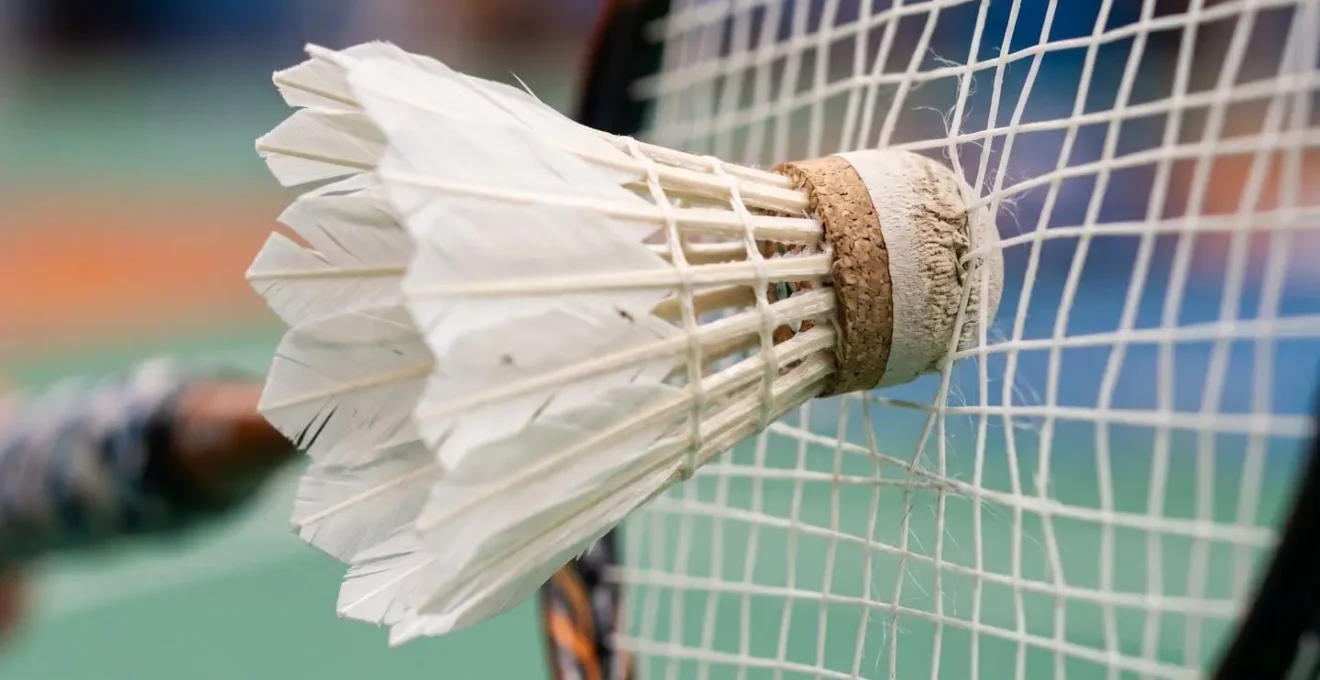 Gros plan sur le contact entre la raquette et le volant lors d'un effet de slice au badminton montrant la rotation et la trajectoire