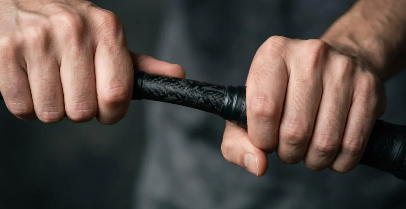 Gros plan sur les mains d'un joueur testant manuellement la flexion d'une tige de raquette
