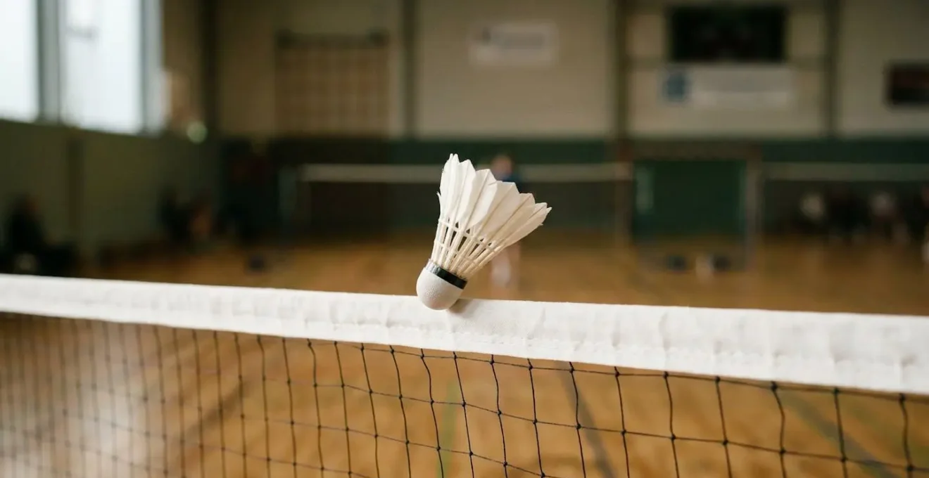 Volant de badminton frôlant la bande du filet après un amorti technique précis