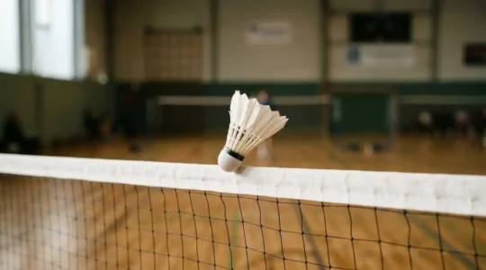 Volant de badminton frôlant la bande du filet après un amorti technique précis