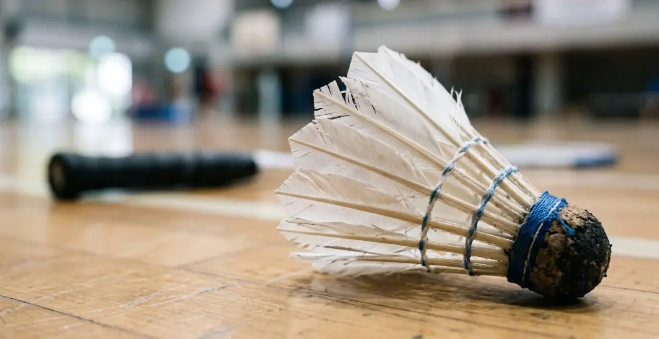 Volant de badminton en gros plan avec raquette floue en arrière-plan suggérant l'entraînement autonome